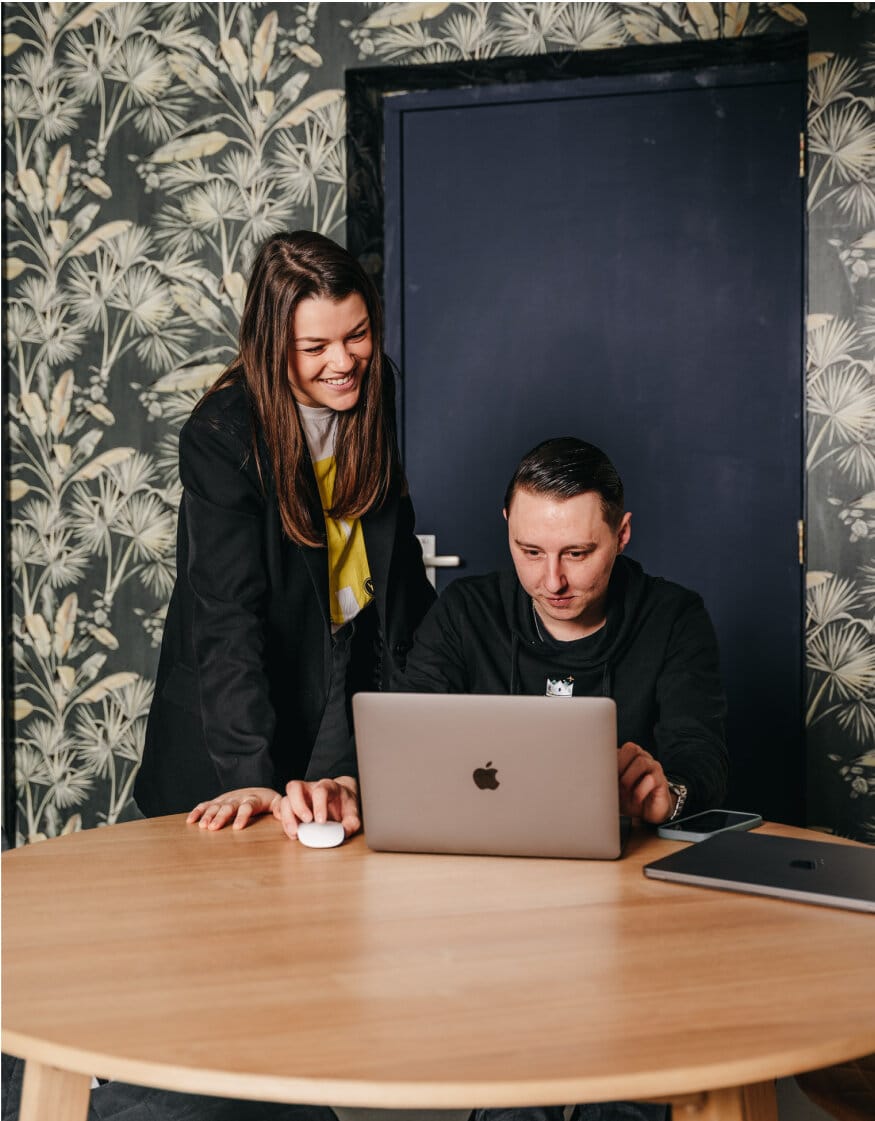 Two people in a meeting room looking at a laptop